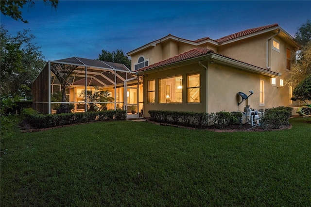 3042 Wentworth Way, Tarpon Springs, FL 34688 - rear view of property featuring a lawn, stucco siding, glass enclosure, and a tiled roof