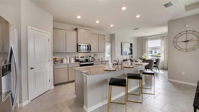 2637 Warren Acres Blvd, Wesley Chapel, FL 33543 - kitchen featuring appliances with stainless steel finishes, gray cabinets, a kitchen breakfast bar, a kitchen island with sink, and recessed lighting