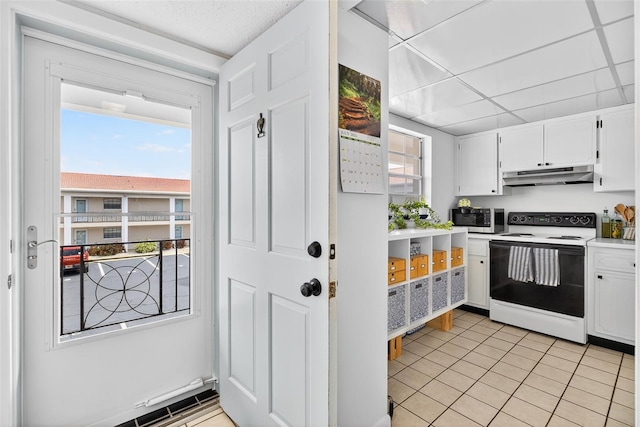 10351 Regal Dr Unit 24, Largo, FL 33774 - kitchen with electric range, under cabinet range hood, stainless steel microwave, white cabinets, and light tile patterned floors