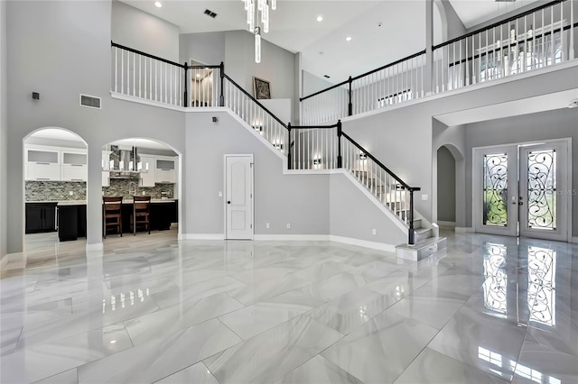3241 Evening Breeze Loop, Wesley Chapel, FL 33544 - unfurnished living room featuring arched walkways, a high ceiling, light marble finish flooring, french doors, and stairway
