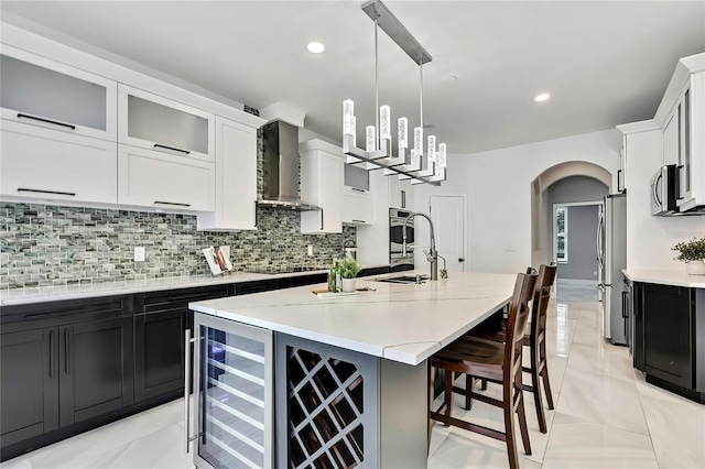3241 Evening Breeze Loop, Wesley Chapel, FL 33544 - kitchen with wall chimney range hood, arched walkways, stainless steel appliances, decorative backsplash, and beverage cooler