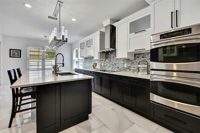 3241 Evening Breeze Loop, Wesley Chapel, FL 33544 - kitchen featuring stainless steel double oven, wall chimney exhaust hood, dark cabinets, white cabinetry, and tasteful backsplash