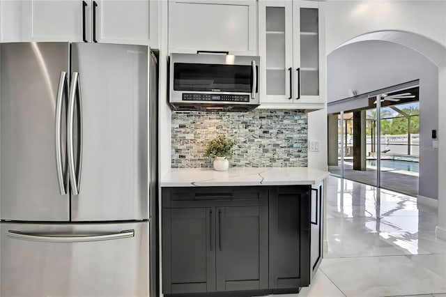 3241 Evening Breeze Loop, Wesley Chapel, FL 33544 - kitchen with stainless steel appliances, decorative backsplash, white cabinets, light stone countertops, and light tile patterned flooring