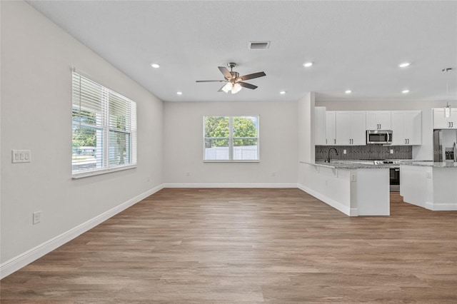 8319 N Ogontz Ave, Tampa, FL 33604 - kitchen with stainless steel appliances, white cabinets, a breakfast bar, light wood-type flooring, and open floor plan