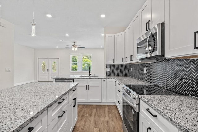 8319 N Ogontz Ave, Tampa, FL 33604 - kitchen with stainless steel appliances, white cabinets, light wood-style flooring, decorative backsplash, and recessed lighting