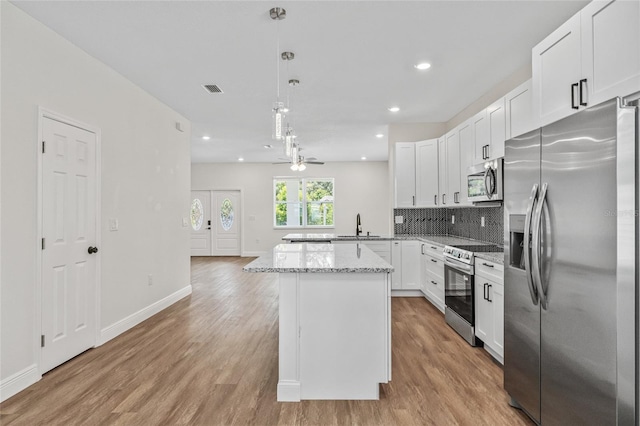 8319 N Ogontz Ave, Tampa, FL 33604 - kitchen featuring appliances with stainless steel finishes, a ceiling fan, light wood finished floors, white cabinets, and tasteful backsplash
