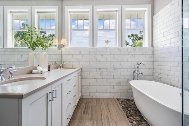 650 Geneva Pl, Tampa, FL 33606 - bathroom featuring tile walls, double vanity, a soaking tub, and wood finished floors