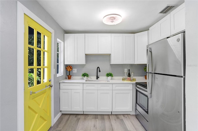 201 83rd Ave N, Saint Petersburg, FL 33702 - kitchen featuring appliances with stainless steel finishes, white cabinetry, light countertops, and light wood-type flooring