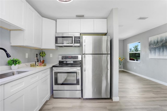 201 83rd Ave N, Saint Petersburg, FL 33702 - kitchen featuring stainless steel appliances, white cabinetry, and light wood-style floors