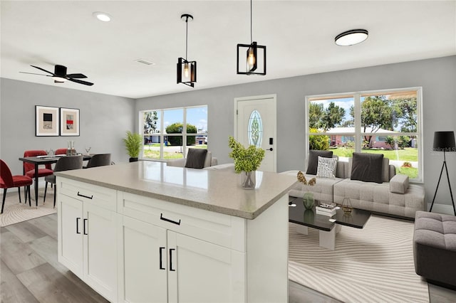 1223 Jasmine Way, Clearwater, FL 33756 - kitchen with open floor plan, light wood-type flooring, decorative light fixtures, a kitchen island, and white cabinetry