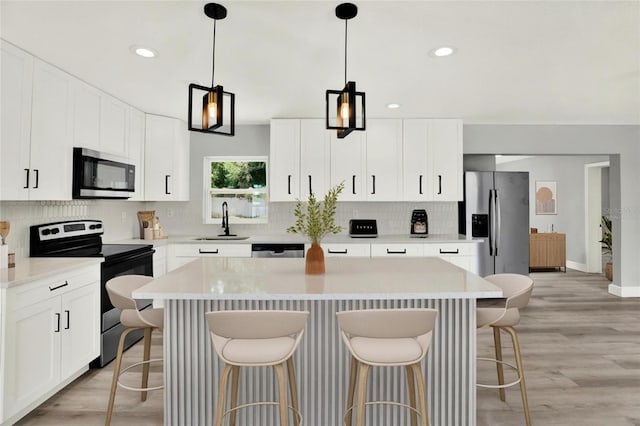 1223 Jasmine Way, Clearwater, FL 33756 - kitchen featuring stainless steel appliances, a kitchen island, decorative backsplash, a kitchen bar, and white cabinets