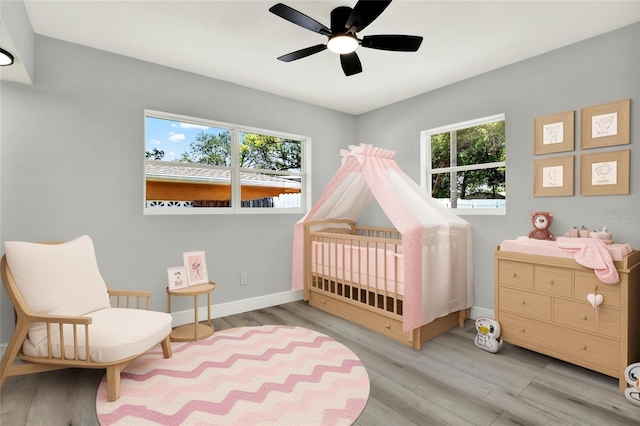 1223 Jasmine Way, Clearwater, FL 33756 - bedroom featuring a crib, wood finished floors, and a ceiling fan