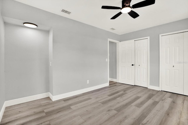1223 Jasmine Way, Clearwater, FL 33756 - unfurnished bedroom featuring multiple closets, wood finished floors, and a ceiling fan