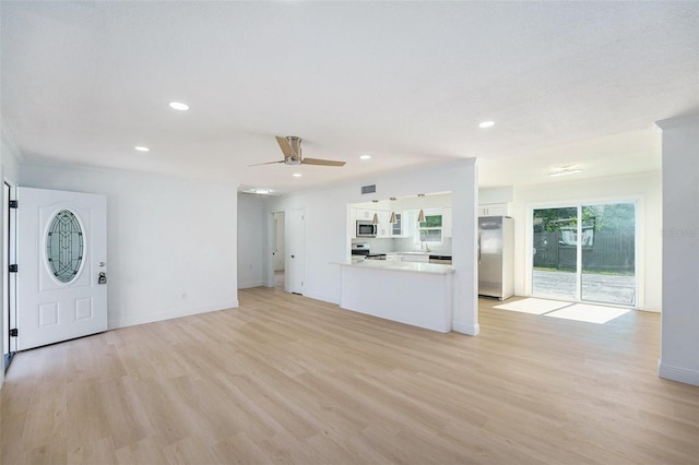 1601 Paloma Ln, Dunedin, FL 34698 - unfurnished living room featuring light wood-style floors, a ceiling fan, recessed lighting, and crown molding