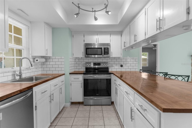 5112 Odin St, Spring Hill, FL 34608 - kitchen with stainless steel appliances, butcher block counters, a raised ceiling, and white cabinetry
