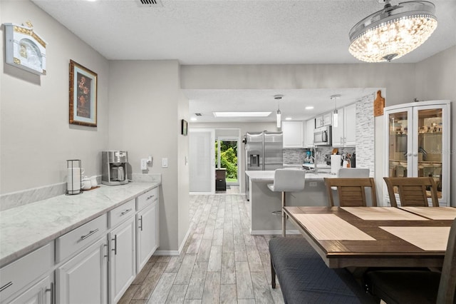 3323 Fox Hunt Dr, Palm Harbor, FL 34683 - dining area with light wood-style floors, a textured ceiling, a chandelier, and recessed lighting