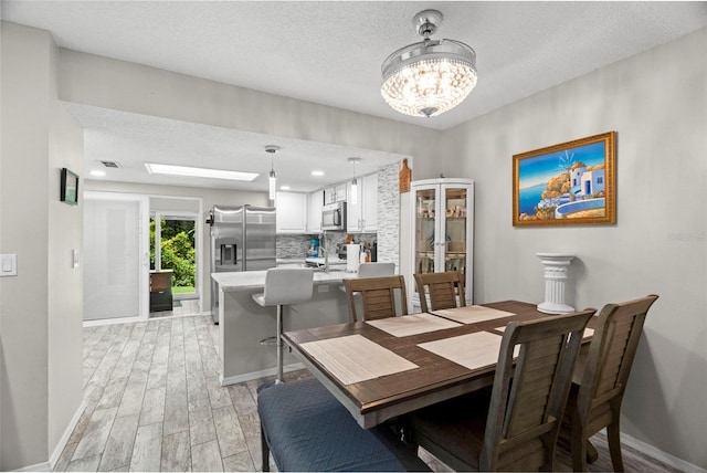 3323 Fox Hunt Dr, Palm Harbor, FL 34683 - dining space with light wood finished floors, a chandelier, and a textured ceiling