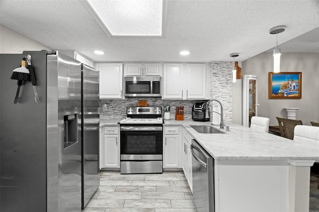3323 Fox Hunt Dr, Palm Harbor, FL 34683 - kitchen featuring appliances with stainless steel finishes, a peninsula, a textured ceiling, decorative backsplash, and white cabinetry