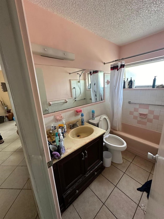 bathroom with a textured ceiling, tile patterned flooring, shower / bath combination with curtain, and vanity