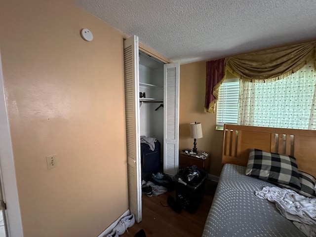 bedroom featuring a closet, wood finished floors, and a textured ceiling