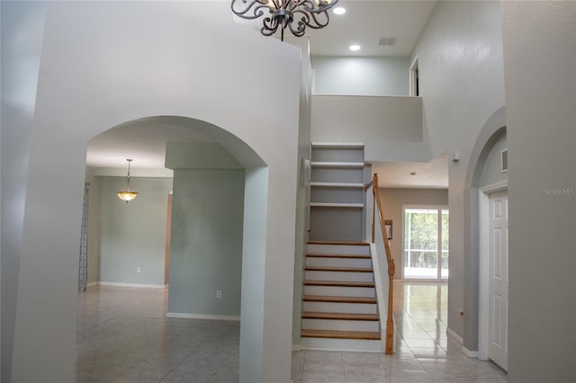 25435 Bruford Blvd, Land O Lakes, FL 34639 - staircase featuring tile patterned floors, a towering ceiling, a chandelier, arched walkways, and recessed lighting