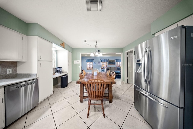 1310 Rustlewood Dr, Brandon, FL 33510 - kitchen with stainless steel appliances, light countertops, white cabinetry, backsplash, and a chandelier