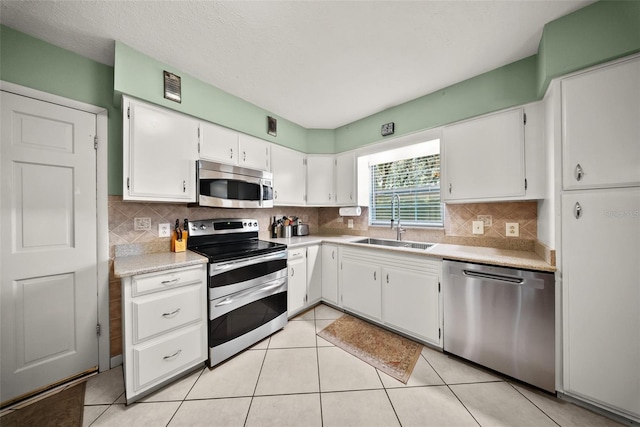 1310 Rustlewood Dr, Brandon, FL 33510 - kitchen with stainless steel appliances, light countertops, white cabinets, decorative backsplash, and light tile patterned floors