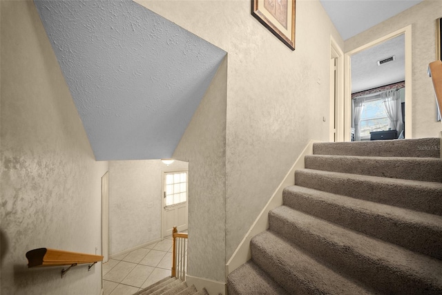 1310 Rustlewood Dr, Brandon, FL 33510 - staircase featuring a textured wall, a textured ceiling, and tile patterned floors