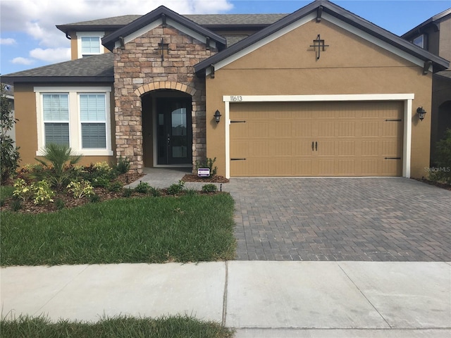 11613 Sweet Tangerine Ln, Tampa, FL 33626 - view of front facade with stone siding, driveway, a garage, and stucco siding