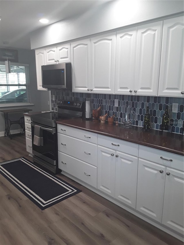 702 Cypress Pl, Sun City Center, FL 33573 - kitchen featuring stainless steel microwave, black range with electric cooktop, dark countertops, dark wood-style floors, and white cabinets