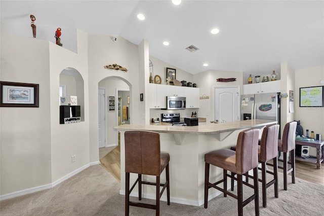 125 Paddock St, Lehigh Acres, FL 33974 - kitchen with stainless steel appliances, a breakfast bar, white cabinetry, lofted ceiling, and recessed lighting