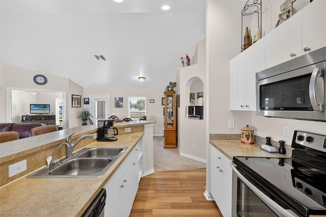 125 Paddock St, Lehigh Acres, FL 33974 - kitchen featuring stainless steel appliances, vaulted ceiling, light wood-style floors, light countertops, and white cabinets