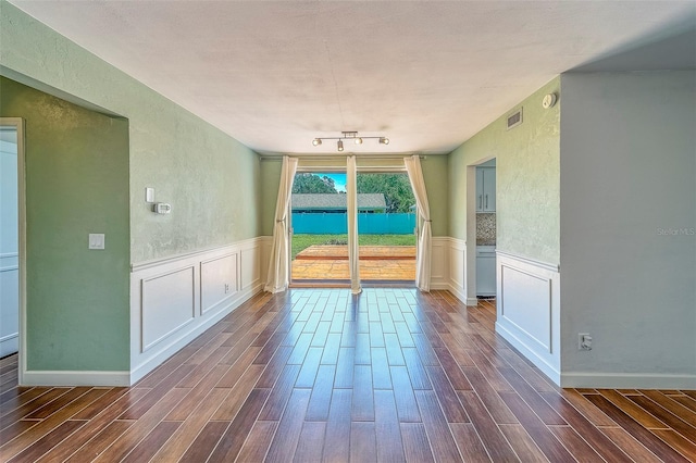 2123 Indigo Dr, Clearwater, FL 33763 - empty room with dark wood-style floors, a wainscoted wall, a decorative wall, and a textured wall