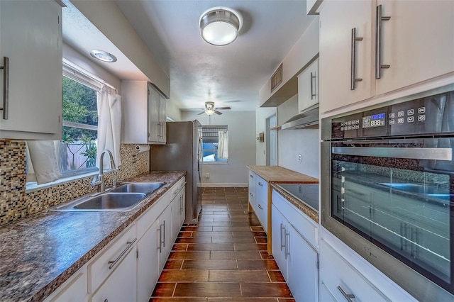2123 Indigo Dr, Clearwater, FL 33763 - kitchen with stainless steel appliances, backsplash, white cabinets, dark wood-style floors, and exhaust hood