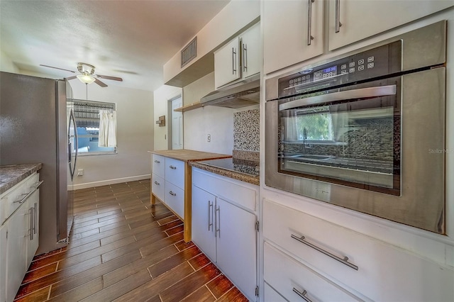 2123 Indigo Dr, Clearwater, FL 33763 - kitchen with appliances with stainless steel finishes, under cabinet range hood, a ceiling fan, tasteful backsplash, and dark wood-type flooring
