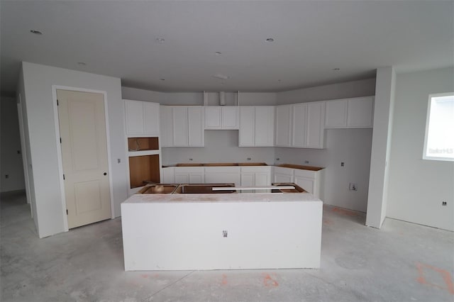 640 Allora Ave, Nokomis, FL 34275 - kitchen with a kitchen island, unfinished concrete floors, and white cabinetry
