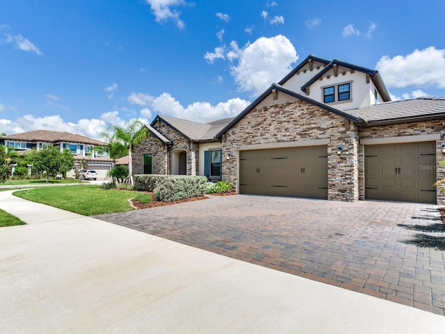 6057 Marsh Trail Dr, Odessa, FL 33556 - view of front of house with a garage, decorative driveway, stone siding, stucco siding, and a tiled roof