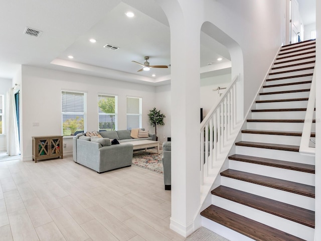6057 Marsh Trail Dr, Odessa, FL 33556 - living room with a ceiling fan, a tray ceiling, stairs, recessed lighting, and light wood finished floors