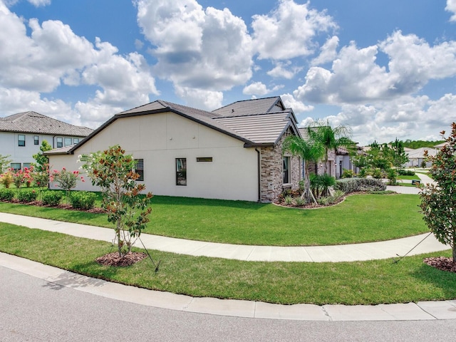 6057 Marsh Trail Dr, Odessa, FL 33556 - view of side of home featuring a yard, stone siding, a tiled roof, and stucco siding