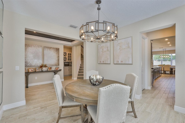 2866 Quail Crest Ct, Valrico, FL 33594 - dining room with a chandelier, light wood finished floors, and stairs