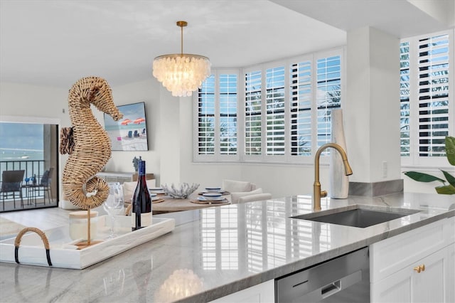 602 Lime Ave Unit 102, Clearwater, FL 33756 - kitchen with stainless steel dishwasher, light stone countertops, a chandelier, white cabinets, and decorative light fixtures