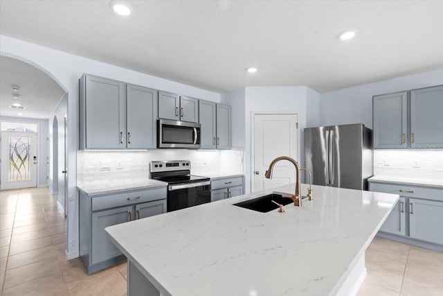 33369 Hamilton Hill Ln, Wesley Chapel, FL 33545 - kitchen with appliances with stainless steel finishes, arched walkways, backsplash, gray cabinets, and light tile patterned floors