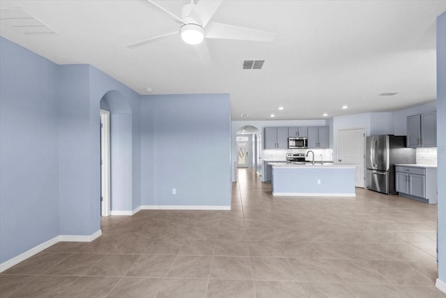 33369 Hamilton Hill Ln, Wesley Chapel, FL 33545 - unfurnished living room with arched walkways, light tile patterned flooring, a ceiling fan, and recessed lighting