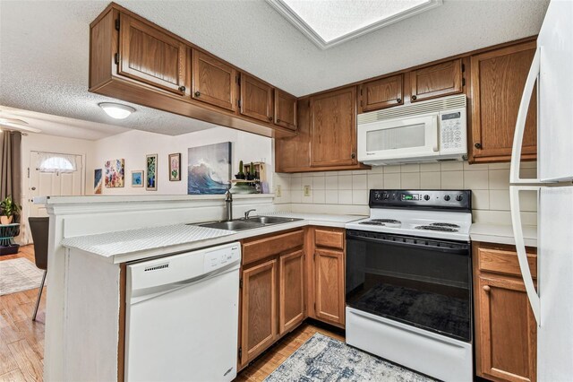3335 Fox Hunt Dr, Palm Harbor, FL 34683 - kitchen featuring white appliances, light wood-style floors, a peninsula, light countertops, and brown cabinetry
