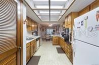 5781 S Utopia Ter, Inverness, FL 34452 - kitchen with freestanding refrigerator, brown cabinetry, and light countertops