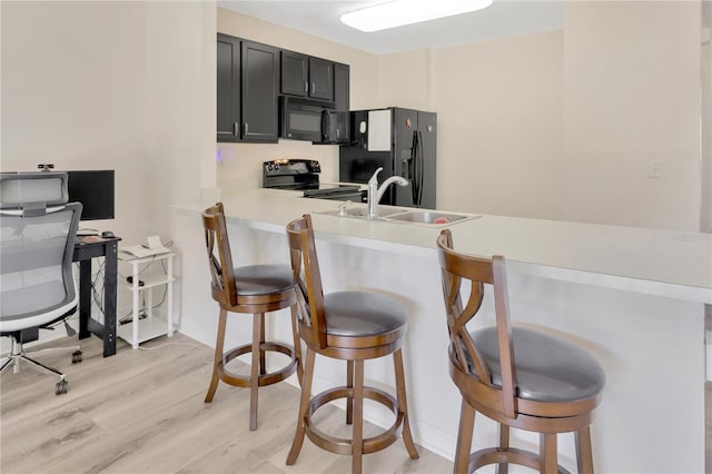 12710 Buffalo Run Dr, Gibsonton, FL 33534 - kitchen featuring black appliances, a breakfast bar, light countertops, and light wood-style flooring