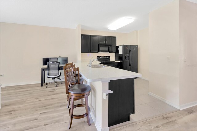 12710 Buffalo Run Dr, Gibsonton, FL 33534 - kitchen with black appliances, light countertops, a kitchen breakfast bar, dark cabinetry, and a peninsula