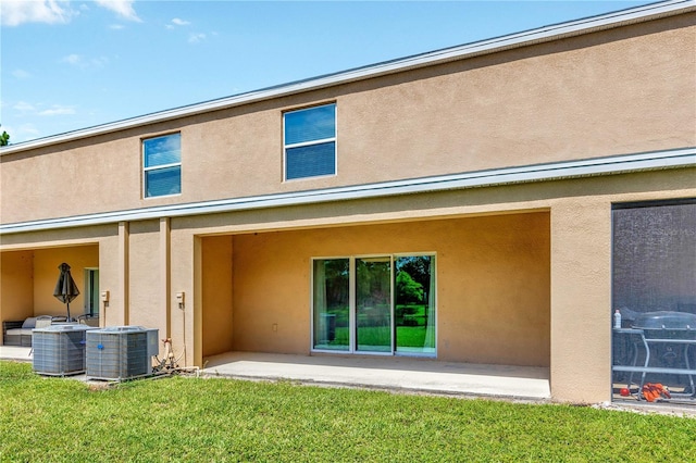 12710 Buffalo Run Dr, Gibsonton, FL 33534 - rear view of house featuring stucco siding, a patio, and a lawn