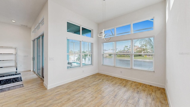 5307 Wishing Arch Dr, Apollo Beach, FL 33572 - unfurnished dining area featuring plenty of natural light, light wood-style flooring, and a towering ceiling