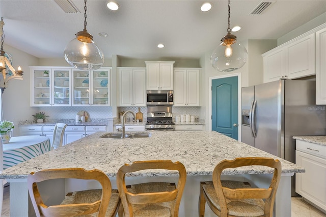 11044 Spring Point Cir, Riverview, FL 33579 - kitchen featuring stainless steel appliances, backsplash, glass insert cabinets, a kitchen island with sink, and white cabinets